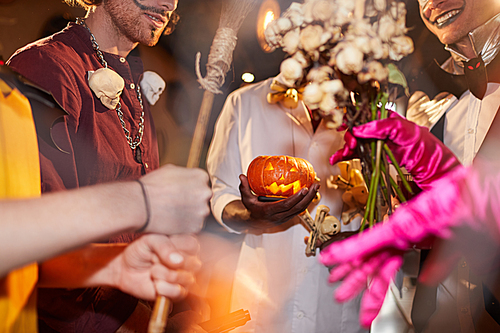 Cropped shot of people wearing Halloween costumes holding carved pumpkin during party in club, copy space