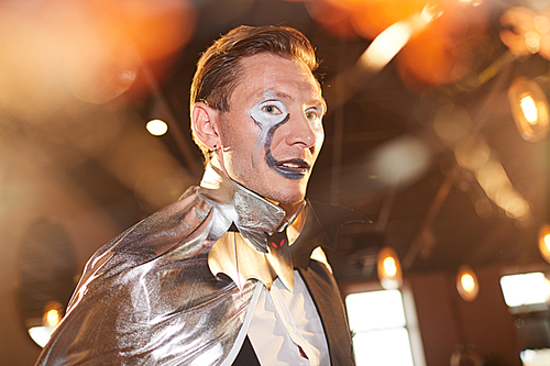 Head and shoulders portrait of adult man wearing Halloween costume posing during stage performance at Halloween party in nightclub, copy space