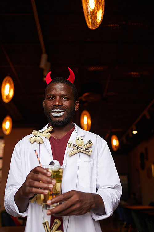 waist up portrait of african-american man wearing  costume posing with drink during party in night club, copy space