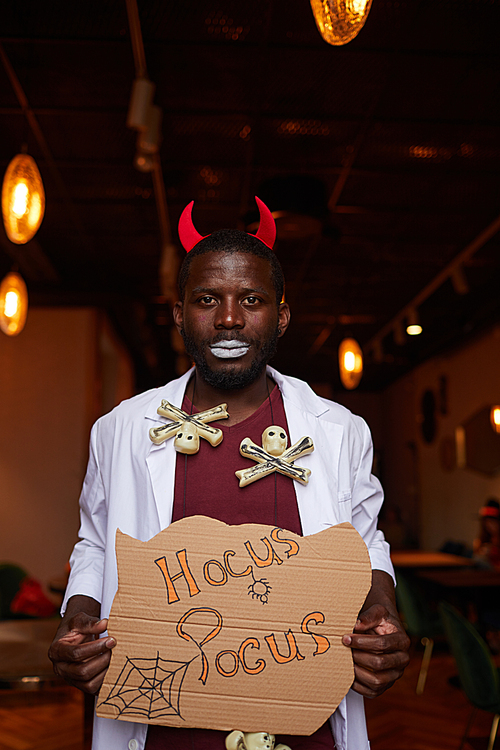 waist up portrait of african-american man wearing  costume posing with hocus pocus sigh during party in nightclub
