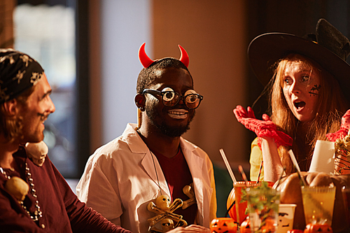 Multi-ethnic group of friends wearing costumes having fun during Halloween party together, copy space