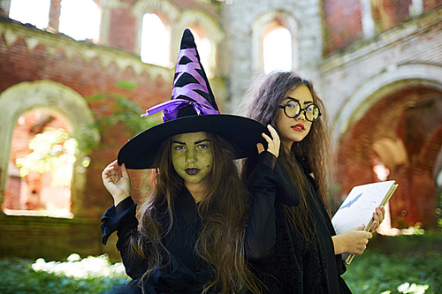 Waist up portrait of two little witches posing in abandoned castle on Halloween, copy space