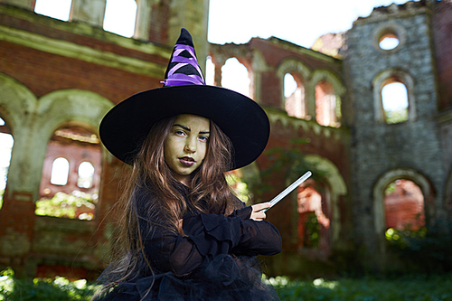 Waist up portrait of teenage witch  while posing in abandoned castle on Halloween, copy space