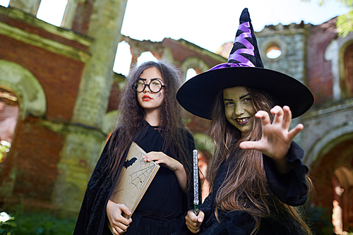Waist up portrait of two teenage witches  while posing in spooky castle on Halloween, copy space
