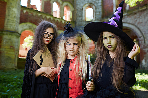 Waist up portrait of three little witches  while posing in spooky castle on Halloween, copy space