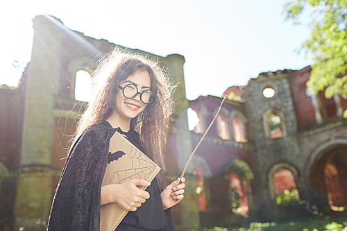 Waist up portrait of little Asian witch posing outdoors on Halloween in bright sunlight, copy space