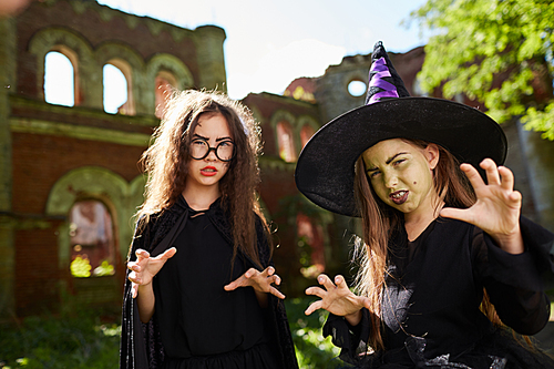 Waist up portrait of two spooky little witches posing outdoors on Halloween, copy space