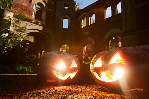Halloween background of two lit Jack o lanterns in front of castle, copy space
