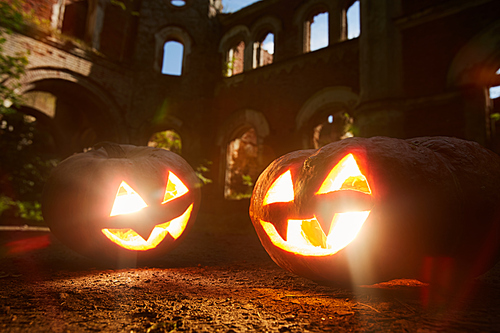 Closeup of two lit Jack o lanterns with castle in background, copy space