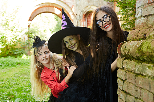 Portrait of three happy little kids going trick-o-treating on Halloween and having fun, copy space