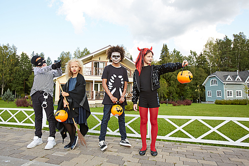 Multi-ethnic group of kids wearing Halloween costumes posing in street while trick or treating, copy space