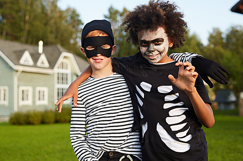 Waist up portrait of two happy boys wearing Halloween costumes  while posing outdoors, copy space