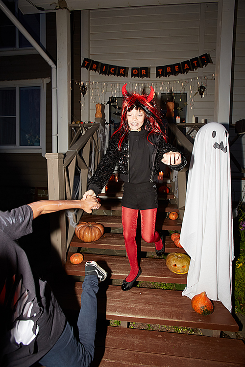 Full length portrait of excited children having fun trick or treating on Halloween, shot with flash