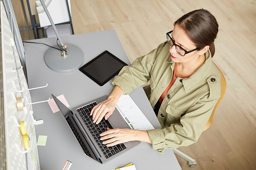 High angle portrait of modern young woman using laptop while sitting at desk , copy space