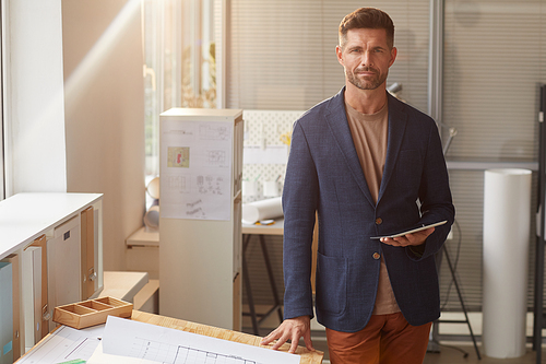 Warm toned portrait of handsome mature man  while standing by desk in office, copy space