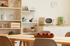 Close up background image of warm-toned kitchen interior with minimal design and wooden table in foreground, copy space