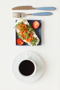 Top view at healthy gourmet breakfast with delicious fitness bruschetta next to cup of black coffee on white table, copy space