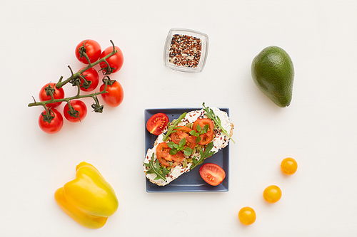 Top view at minimal composition of fitness bruschetta with cherry tomatoes and herbs decorated by healthy breakfast ingredients on white background, copy space