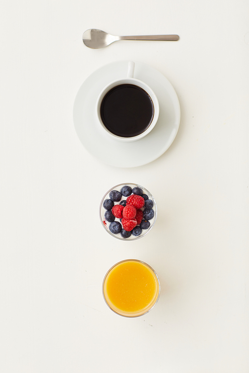 Top view at minimal composition of delicious dessert decorated with fresh berries next to coffee cup on white background, breakfast concept, copy space