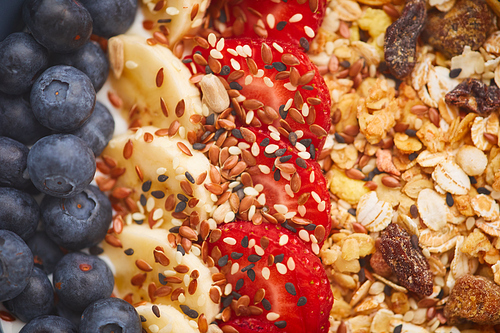 Above view close up of delicious granola dessert decorated with fruit and berries with sesame seeds, healthy breakfast concept, copy space