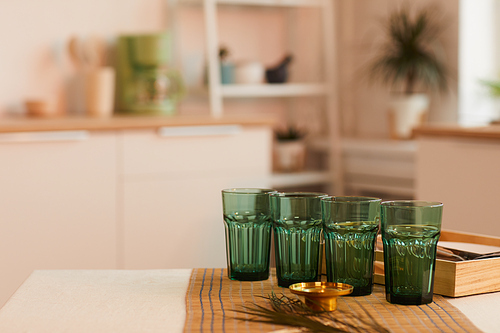 Warm toned background image of green glasses on kitchen table in minimal interior, ready for serving, copy space