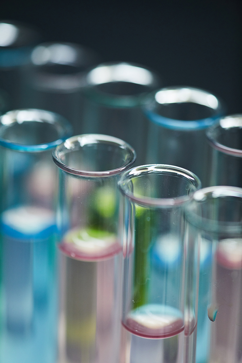 Extreme close up background of test tubes with colored liquid on table in research laboratory, copy space
