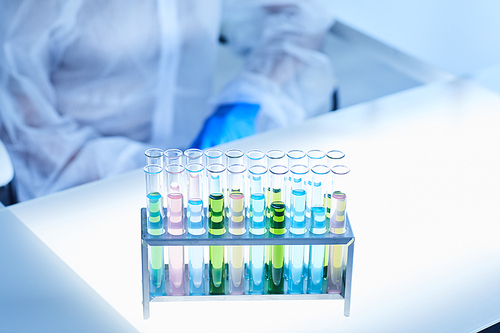 Background image of test tubes with colored liquid on table in blue lit laboratory, copy space