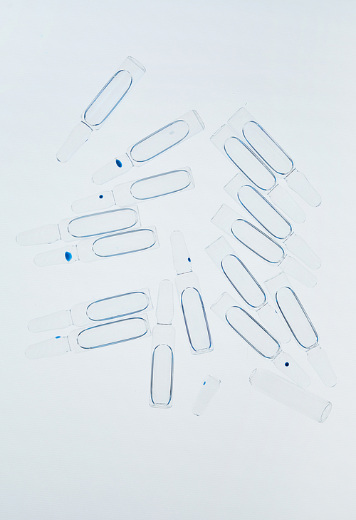Top view background image of glass ampules scattered on white table in laboratory, copy space