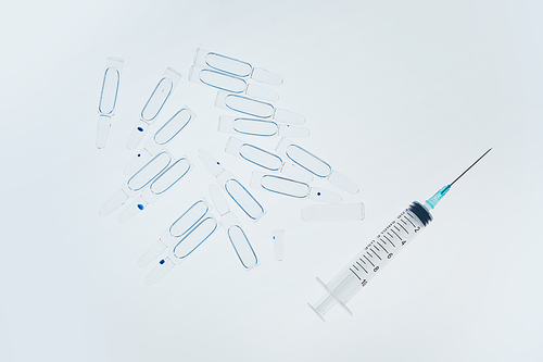 Top view background image of syringe and glass ampules scattered on white table in medical laboratory, copy space