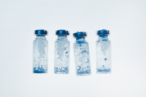 Top view background image of glass vials in row on white table in medical laboratory, copy space