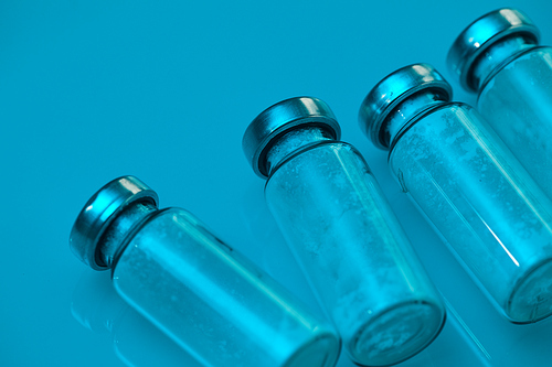Close up background of glass vials in row on blue in medical laboratory, copy space