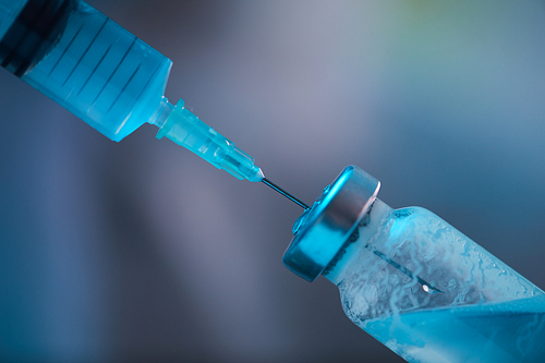 Extreme closeup of syringe needle taking medicine from glass vial, medical background with copy space