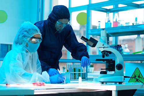 Portrait of two scientist wearing full protective gear working on research in medical laboratory, copy space