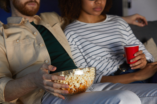 Cropped portrait of mixed-race modern couple watching movie while enjoying date in cinema