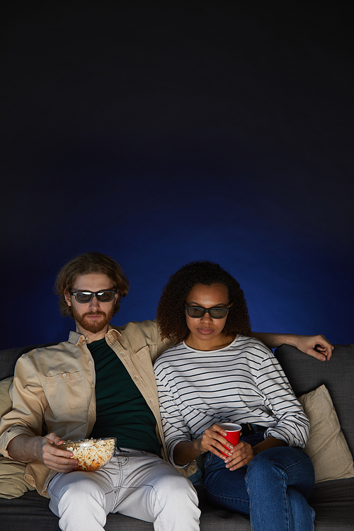 Portrait of mixed-race modern couple watching movie and wearing stereo glasses while enjoying date in cinema, copy space