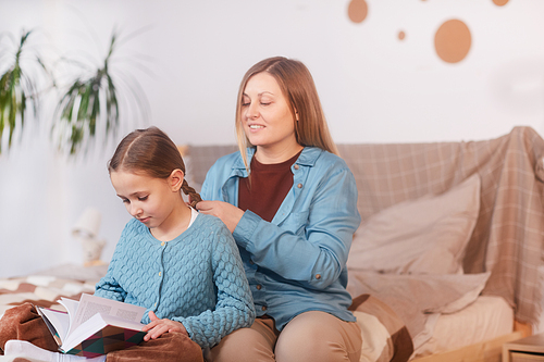 Portrait of adult mother brainding hair of little girl while getting ready for school in morning, copy space