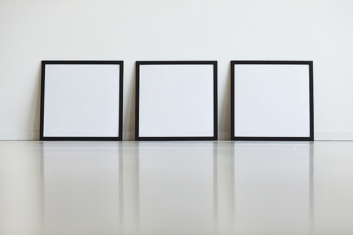 Background image of three identical black frames set against white wall in row at art gallery, copy space