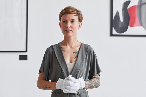 Waist up portrait of tattooed creative woman  while standing against white wall in modern art gallery exhibition, copy space