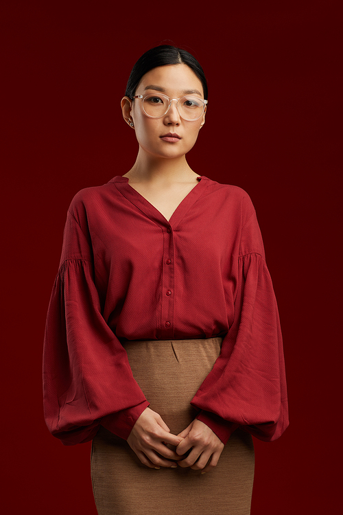 Professional portrait of elegant Asian woman standing by maroon background and 