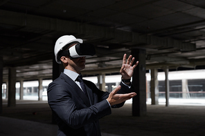 Dramatic waist up portrait of businessman wearing VR gear at construction site while visualizing future project in 3D, copy space