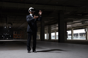 Dramatic full length portrait of businessman wearing VR gear at construction site while visualizing future project in 3D, copy space