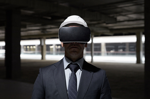 Dramatic front view portrait of businessman wearing VR gear at construction site while visualizing future project in 3D, copy space