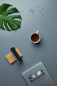 Above view flat lay of tropical leaf and business accessories over grey workplace background, copy space