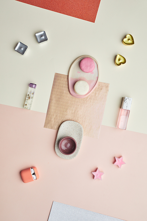 Minimal background image of pink pastel-colored objects earphones and perfume bottle laid out in graphic composition, copy space