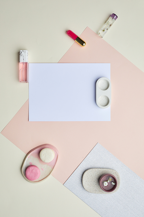 Minimal graphic composition of blank white paper and makeup on pastel-colored background, copy space