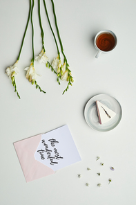Minimal background composition of cup of tea and cake on table with floral details and lettering the most wonderful time, copy space
