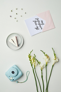 Minimal background composition of instant camera on table with floral details and lettering the most wonderful time, copy space