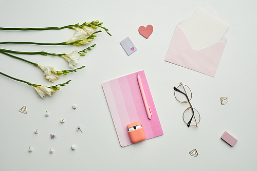 Minimal background composition of female themed stationary, accessories and eyeglasses on white table with floral decor, copy space