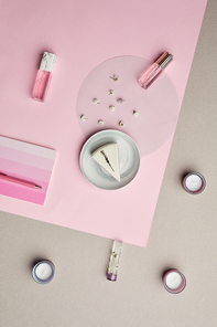 Minimal composition of perfume bottles and cake over pink graphic background, copy space