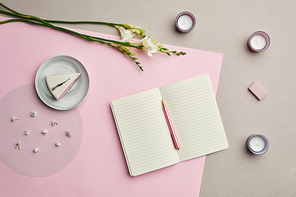 Minimal composition of blank planner over pink graphic background with floral decor, copy space